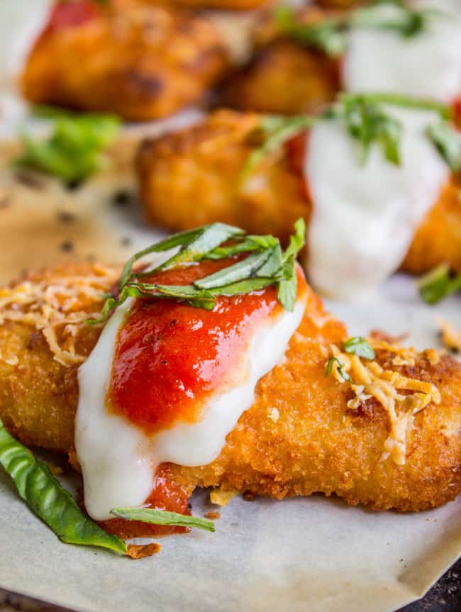 crispy fish stick topped with fresh mozzarella, tomato sauce, and basil on a white plate. 