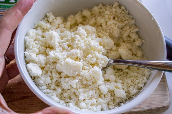 Crumbled up cotija cheese in a white bowl. 