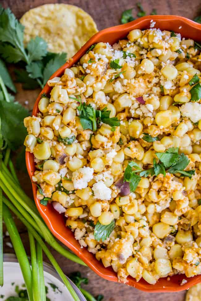Mexican Corn Dip in a red bowl with chips and cilantro in the background. 