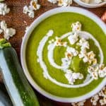 a bowl of zucchini soup topped with popcorn.