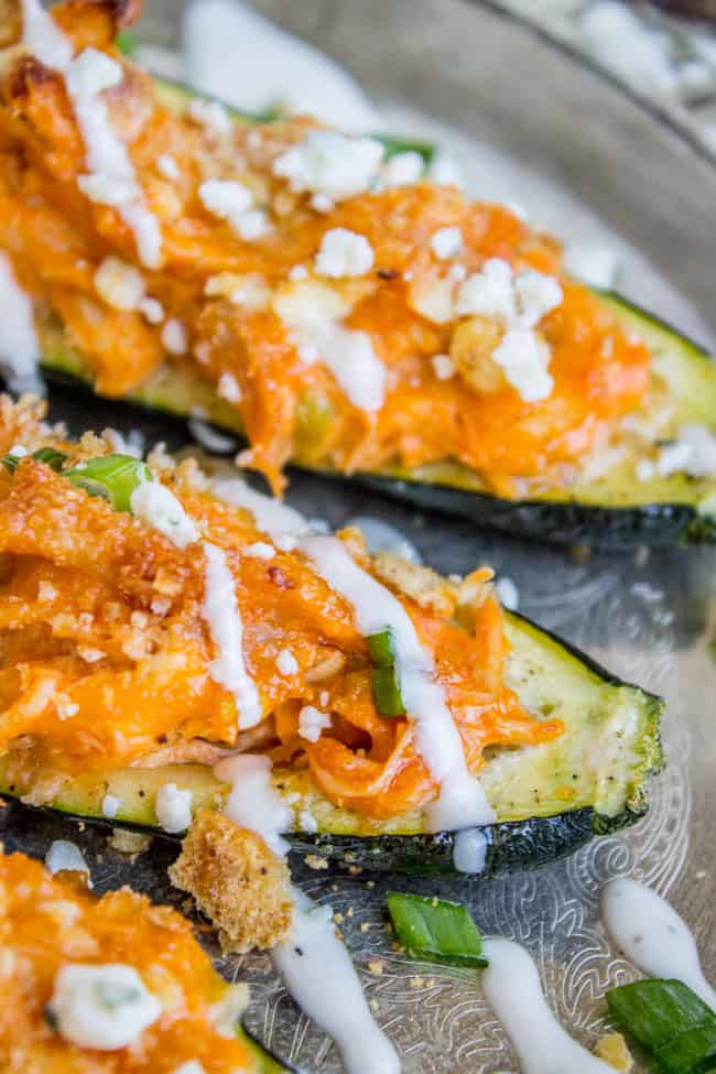 close of buffalo chicken in zucchini boat with scallions, crackers and ranch dressing.