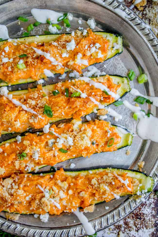 Buffalo Chicken Zucchini Boats toped with blue cheese and ranch dressing on a silver tray.