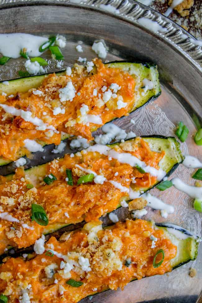 Buffalo Chicken Zucchini Boats toped with blue cheese and ranch dressing on a silver tray.