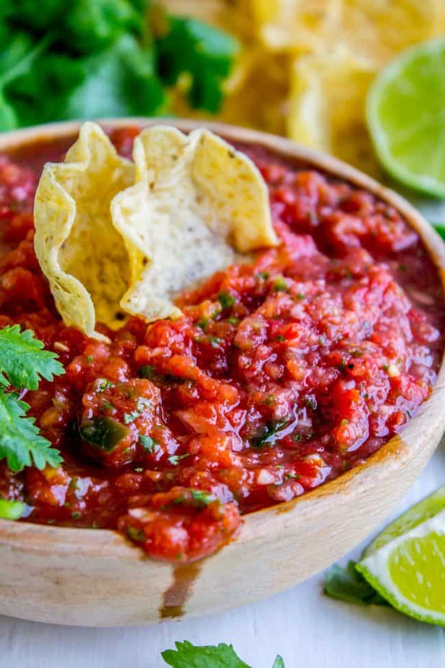 salsa in a brown bowl with two tortilla chips in it. 