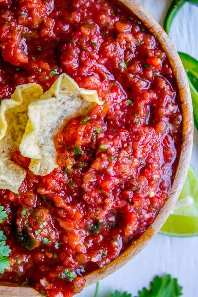 fresh homemade salsa in a brown bowl with tortilla chips in it scooping up salsa. 