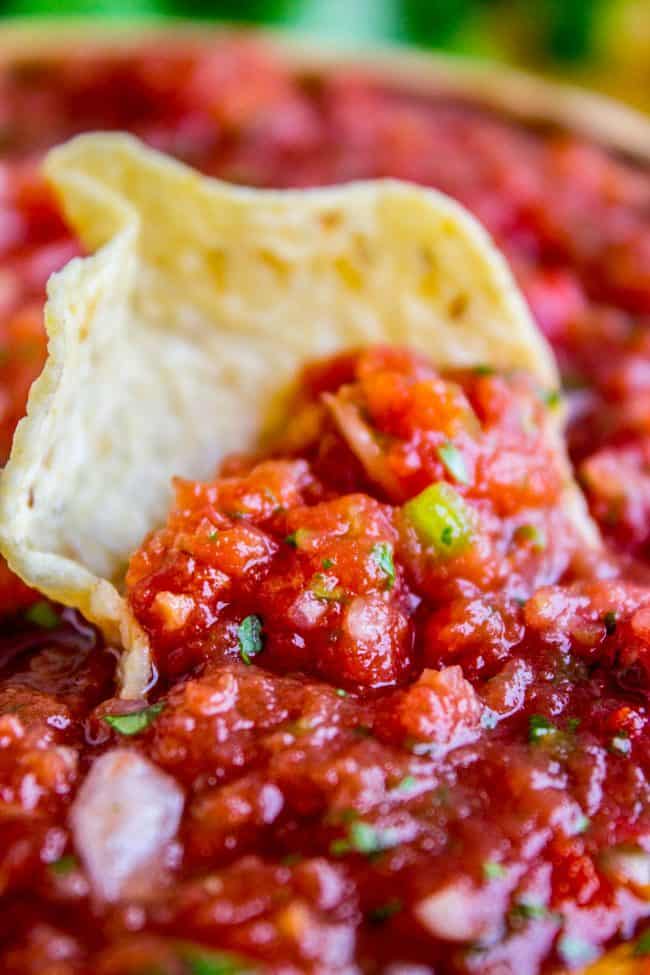 close up of a tortilla chip dipped into homemade salsa. 