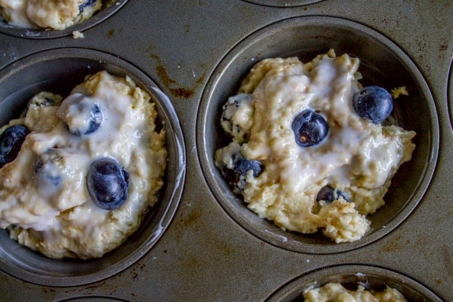 blueberry muffin batter in a muffin tin.