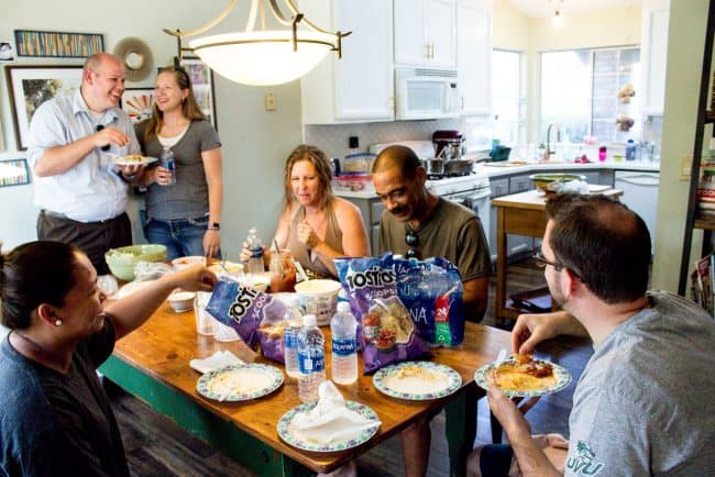 Friends gathered at the kitchen table to enjoy a meal together. 