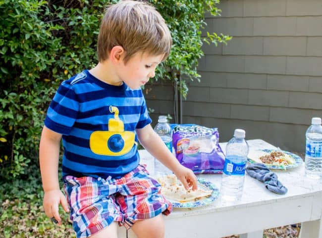 Child eating a taco in the backyard. 