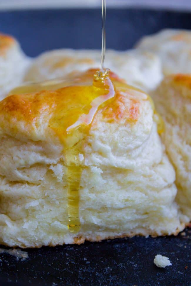 fluffy buttermilk biscuits with honey being drizzled on top.