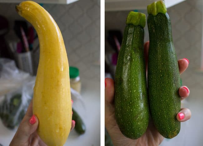 A hand holding up one yellow squash and two zucchinis. 
