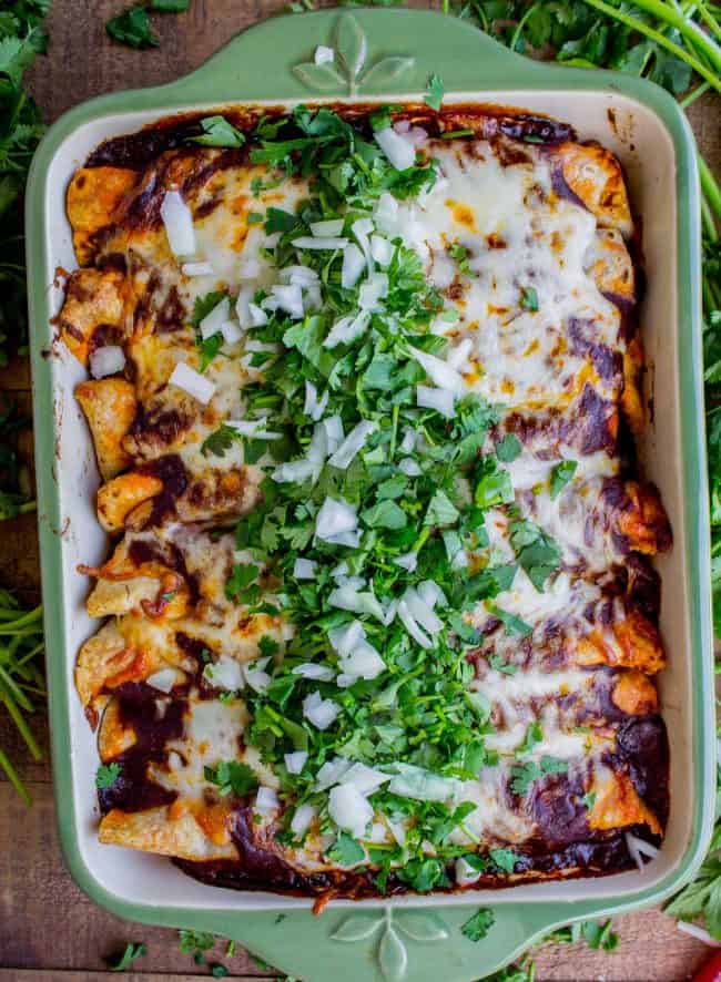 sweet potato and black bean enchiladas topped with cilantro and onions in a baking dish.