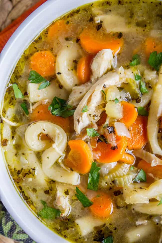 Chicken Noodle Soup with Homemade Noodles from The Food Charlatan. Is there anything more comforting than homemade Chicken Noodle Soup? Carrots, onions, celery...the smell is enough to bring you back. This recipe uses dark and white meat from a rotisserie chicken, and homemade noodles (or you can totally use store-bought). It's nostalgia in a bowl! #chicken #noodles #homemade #soup #comfortfood #healthy #easy #carrots #celery #rotisserie Chicken noodle soup in a white bowl with homemade noodles.