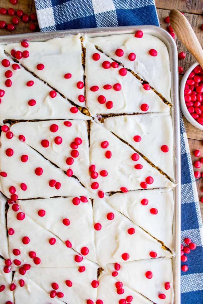 Sheet pan of pumpkin bars with frosting and red hots.