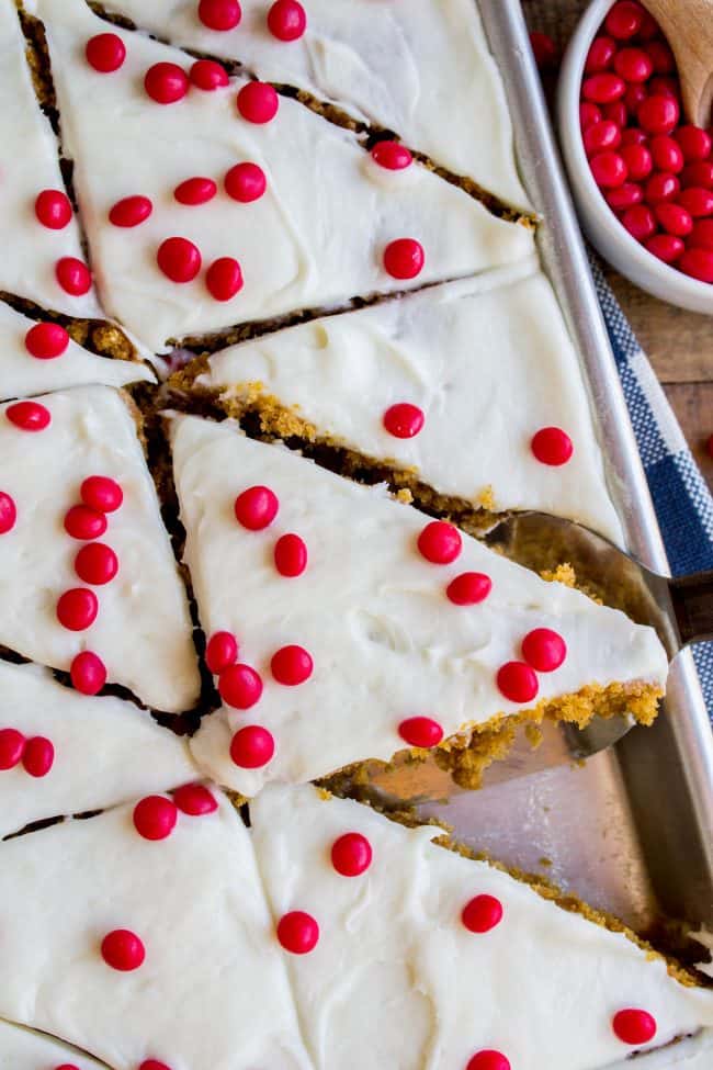 Pumpkin Bars with Cream Cheese Frosting and red hots in a sheet pan with a blue and white napkin.