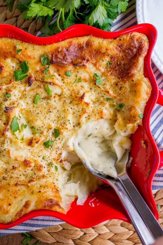 make ahead mashed potatoes in a red serving dish with spoon.