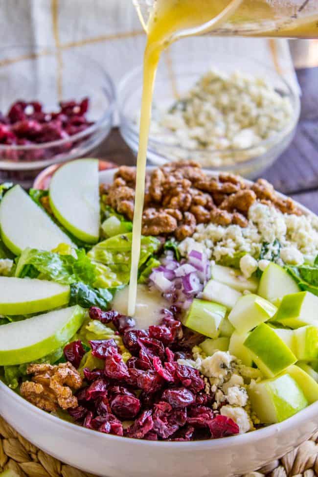 apple gorgonzola salad with homemade dressing being poured on top.