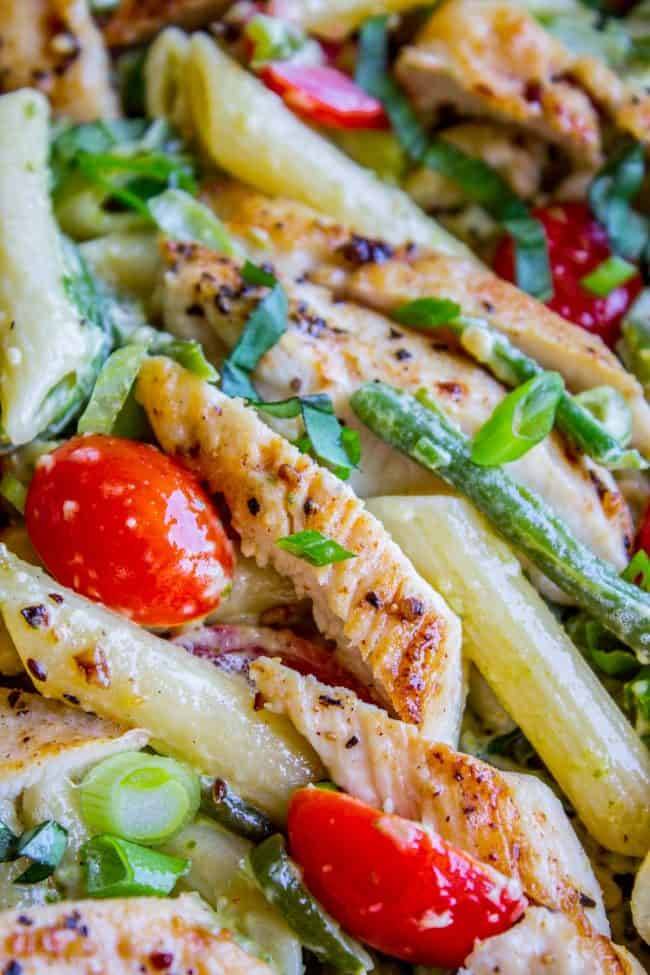 30 Minute Pesto Penne with Chicken and Cherry Tomatoes from The Food Charlatan. This 30 Minute Pesto Penne Chicken is your new favorite last minute dinner! It's done so quick, you can even used canned chicken if you are really crunched for time. Swap the frozen green beans and cherry tomatoes for whatever veggies you have on hand! #pesto #pasta #cherrytomatoes #easydinner #fast #greenbeans #chicken #penne #basil #greenonions #mayonnaise #skillet #dinner #easydinner #healthy #healthydinner close up of chicken penne pesto pasta with cherry tomatoes.