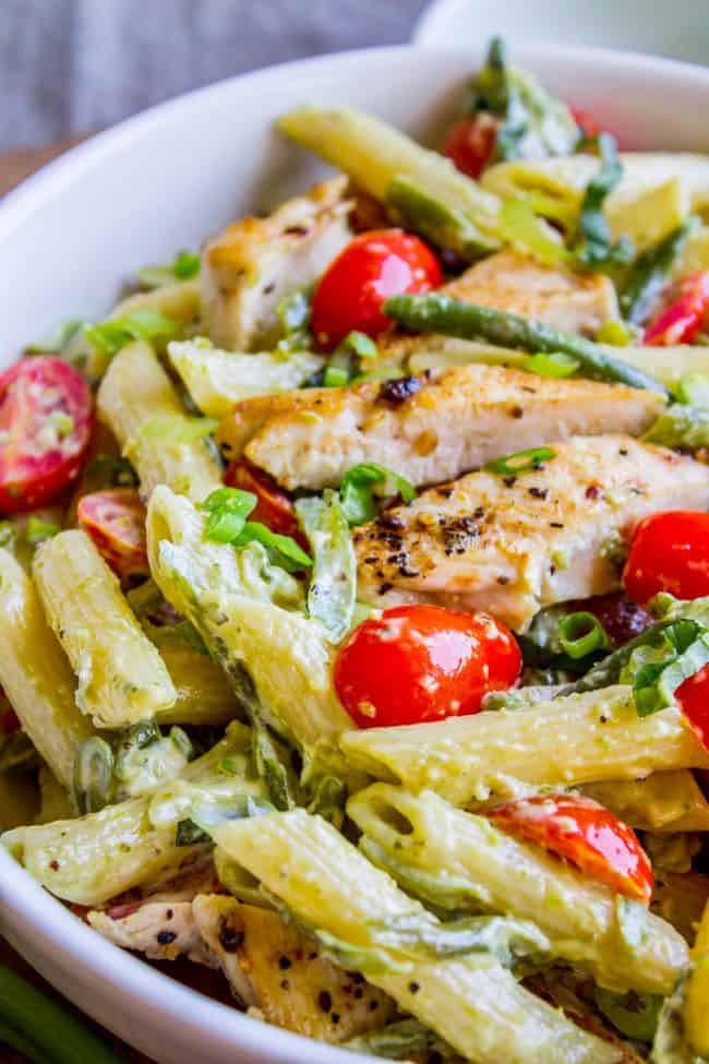 30 Minute Pesto Penne with Chicken and Cherry Tomatoes from The Food Charlatan. This 30 Minute Pesto Penne Chicken is your new favorite last minute dinner! It's done so quick, you can even used canned chicken if you are really crunched for time. Swap the frozen green beans and cherry tomatoes for whatever veggies you have on hand! #pesto #pasta #cherrytomatoes #easydinner #fast #greenbeans #chicken #penne #basil #greenonions #mayonnaise #skillet #dinner #easydinner #healthy #healthydinner chicken penne pesto with cherry tomatoes in a white bowl.