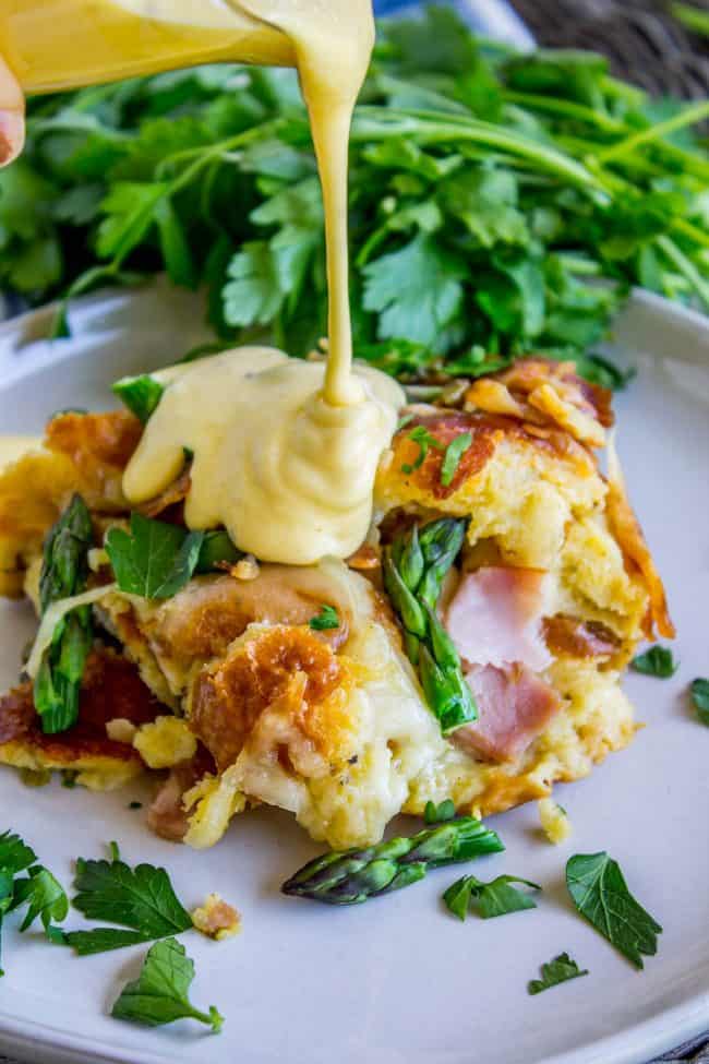 breakfast casserole with hollandaise sauce being poured on it.