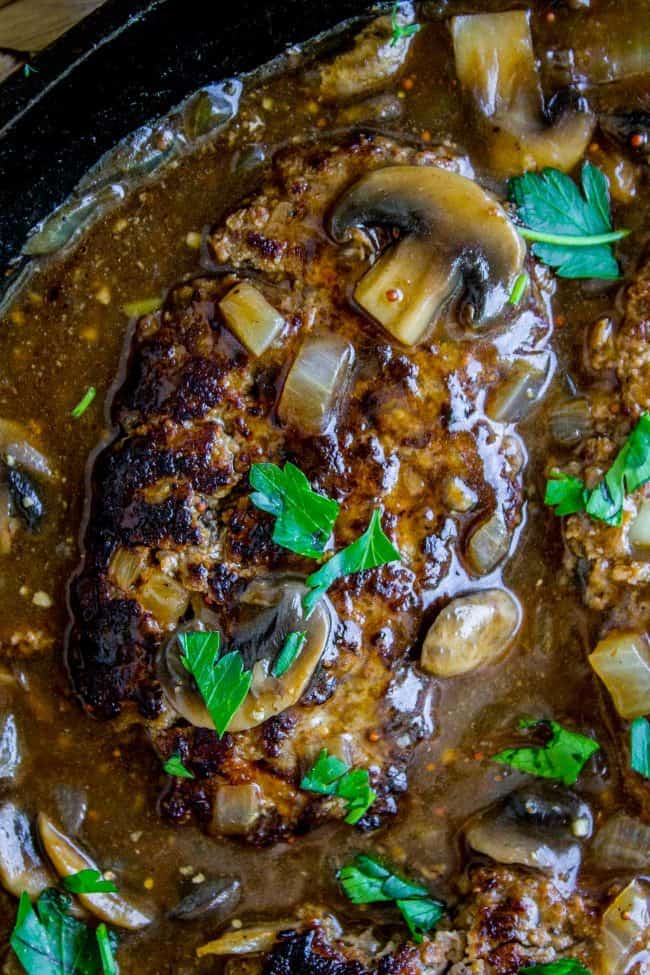 Salisbury Steak with Mushroom Gravy (30 Minute dinner) from The Food Charlatan. Salisbury Steak sounds so fancy but it's SO easy to make. They are basically mini meatloaves fried and served with mushroom gravy. It's the perfect comfort food and only takes 30 minutes to make. You have to serve this with Creamy Mashed Potatoes to get the full effect! #ComfortFood #Easy #30minutes #dinner #oneskillet #beef #groundbeef #mashedpotatoes #gravy #mushrooms #sauce #hamburger #fromscratch salisbury steak with mushroom gravy in a cast iron skillet.