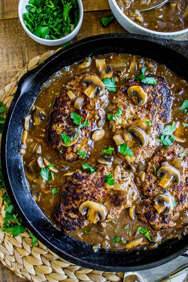 Salisbury Steak with Mushroom Gravy (30 Minute dinner) from The Food Charlatan. Salisbury Steak sounds so fancy but it's SO easy to make. They are basically mini meatloaves fried and served with mushroom gravy. It's the perfect comfort food and only takes 30 minutes to make. You have to serve this with Creamy Mashed Potatoes to get the full effect! #ComfortFood #Easy #30minutes #dinner #oneskillet #beef #groundbeef #mashedpotatoes #gravy #mushrooms #sauce #hamburger #fromscratch salisbury steak recipe with mushroom gravy sauce in a cast iron skillet.