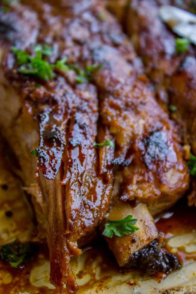 Honey Balsamic Slow Cooker Pork Ribs from The Food Charlatan. These slow cooker pork ribs are fall-off-the-bone delicious! The slow cooker makes them incredibly tender and moist, and the honey balsamic glaze just doesn't need an explanation. Does it?? They are SO easy to make! #ribs #porkribs #spareribs #honey #balsamic #balsamicvinegar #slowcooker #crockpot #glazed #pork closeup of slow cooker spare ribs garnished with fresh herbs