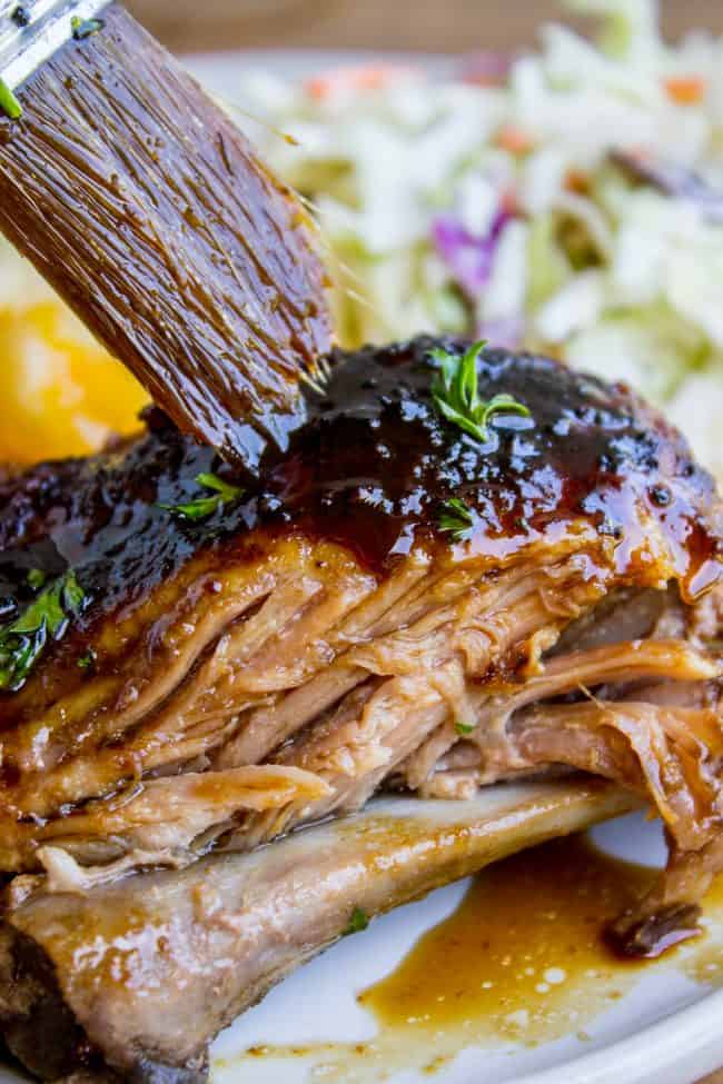 Honey Balsamic Slow Cooker Pork Ribs from The Food Charlatan. These slow cooker pork ribs are fall-off-the-bone delicious! The slow cooker makes them incredibly tender and moist, and the honey balsamic glaze just doesn't need an explanation. Does it?? They are SO easy to make! #ribs #porkribs #spareribs #honey #balsamic #balsamicvinegar #slowcooker #crockpot #glazed #pork slow cooker pork ribs being brushed with honey balsamic glaze