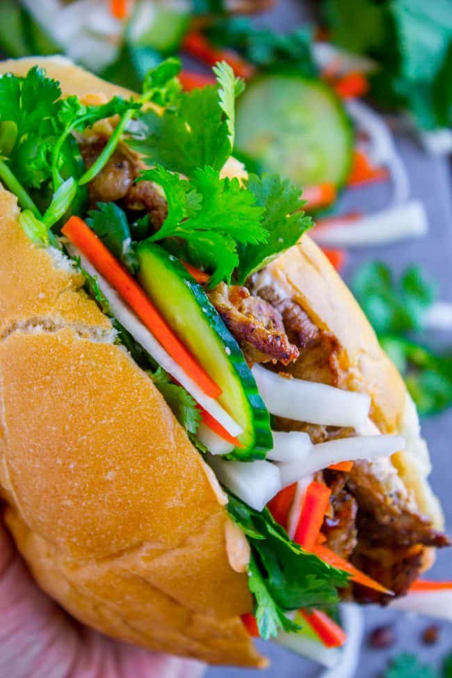 Banh Mi Sandwich from The Food Charlatan. These traditional Vietnamese Banh Mi Sandwiches will blow your mind! A mini soft baguette, smeared with sriracha mayo, topped with thinly sliced marinated pork, pickled veggies, and tons of cilantro. It's heaven! #vietnam #banhmi #sandwich #vietnamese #cilantro #daikon #pickled #carrots #baguette #recipe #pork #howtomake #pickledvegetables #sauce #sriracha #mayonnaise banh mi recipe.