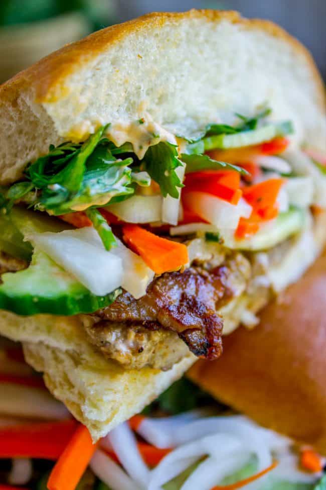 Banh Mi Sandwich from The Food Charlatan. These traditional Vietnamese Banh Mi Sandwiches will blow your mind! A mini soft baguette, smeared with sriracha mayo, topped with thinly sliced marinated pork, pickled veggies, and tons of cilantro. It's heaven! #vietnam #banhmi #sandwich #vietnamese #cilantro #daikon #pickled #carrots #baguette #recipe #pork #howtomake #pickledvegetables #sauce #sriracha #mayonnaise banh mi sandwich.