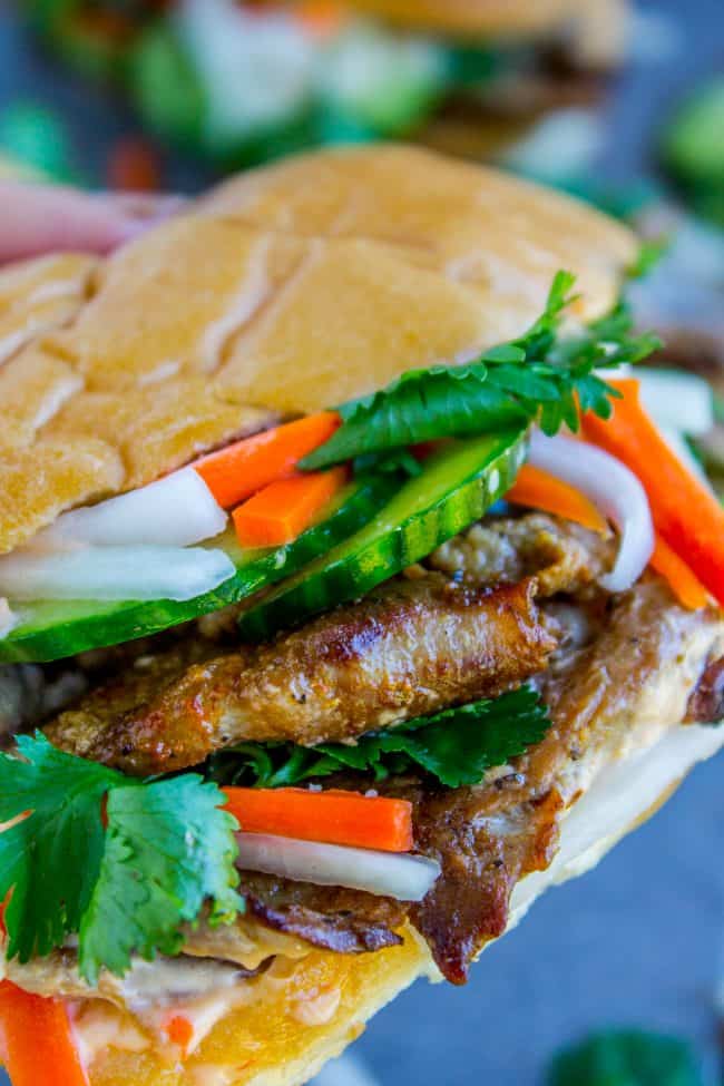 Banh Mi Sandwich from The Food Charlatan. These traditional Vietnamese Banh Mi Sandwiches will blow your mind! A mini soft baguette, smeared with sriracha mayo, topped with thinly sliced marinated pork, pickled veggies, and tons of cilantro. It's heaven! #vietnam #banhmi #sandwich #vietnamese #cilantro #daikon #pickled #carrots #baguette #recipe #pork #howtomake #pickledvegetables #sauce #sriracha #mayonnaise banh mi sandwich.