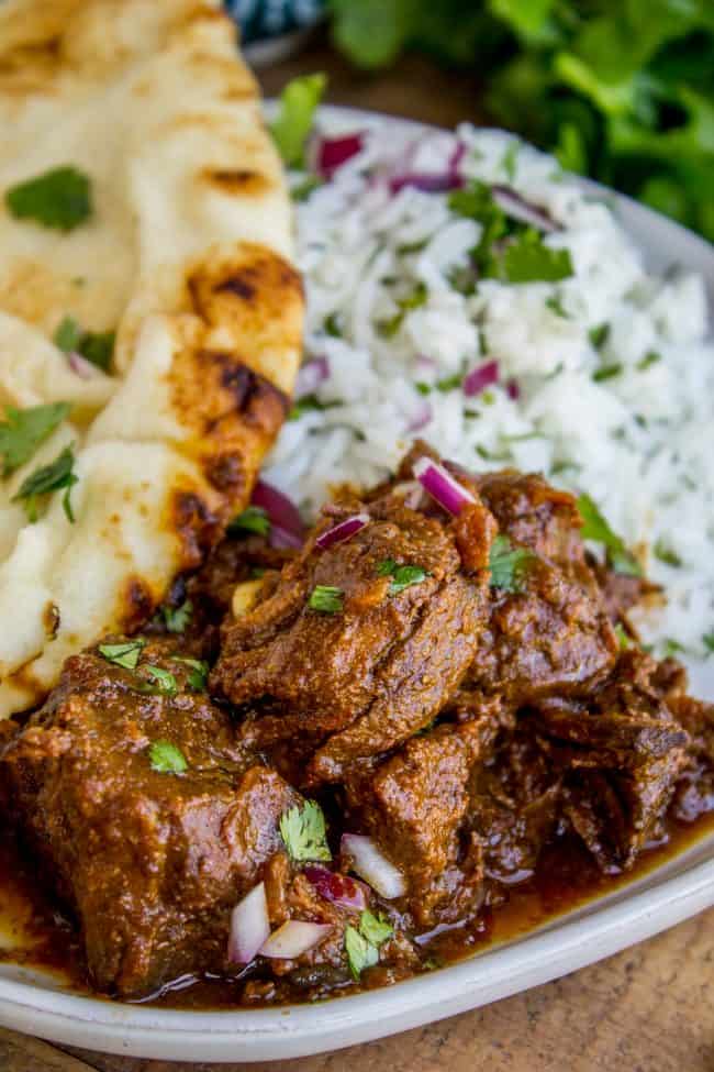 Slow Cooker Beef Curry from The Food Charlatan. This slow cooker beef curry could not be easier! Thick chunks of slow-cooked, tender beef, in a rich and thick curry sauce that is just waiting to be scooped up with some naan. #curry #beef #beefcurry #indian #indianfood #yellow #rice #naan #cilantro #tender #crockpot #slowcooker beef curry with rice and naan.