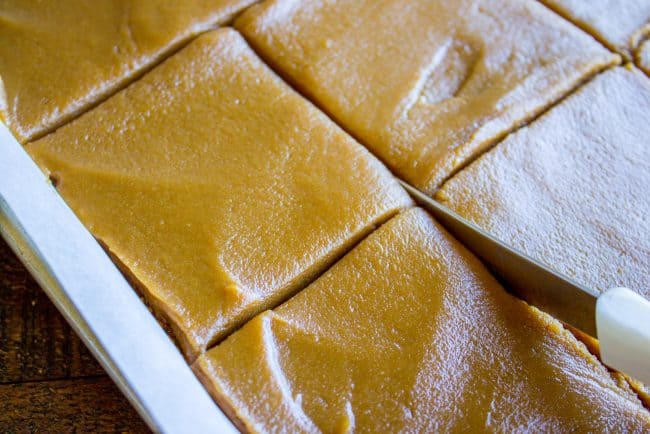 Caramel Cake with Caramel Icing Recipe from The Food Charlatan. Have you ever made a Caramel Cake with Caramel Icing recipe? It's a classic Southern treat! But instead of a layer cake, I made it into a thin sheet cake. Less time baking, more time eating, I say! It's really easy to put together. #southern #icing #recipe #caramel #frosting #cake #sheetcake #oldfashioned #easy #homemade A knife cutting a frosted caramel cake recipe into squares
