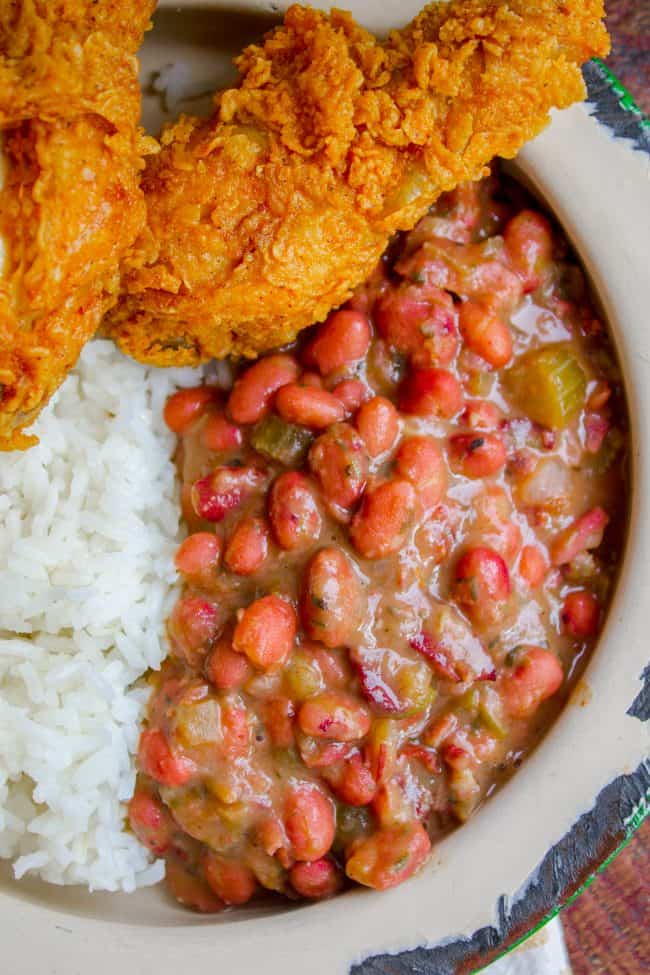 Red Beans and Rice (Better Than Popeye's!) from The Food Charlatan. Have you ever had traditional Red Beans and Rice? It's a southern staple! I tried Popeye's Red Beans and Rice for the first time a while back, but these beans are even better. They are so creamy and flavorful, with the perfect smoky Cajun spice! #redbeansandrice #riceandbeans #beans #rice #ham #hambone #smokey #traditional #southern #cajun #neworleans #popeyes #recipe #easy #stovetop #authentic #withham #Louisiana #best #creamy red beans and rice with fried chicken.