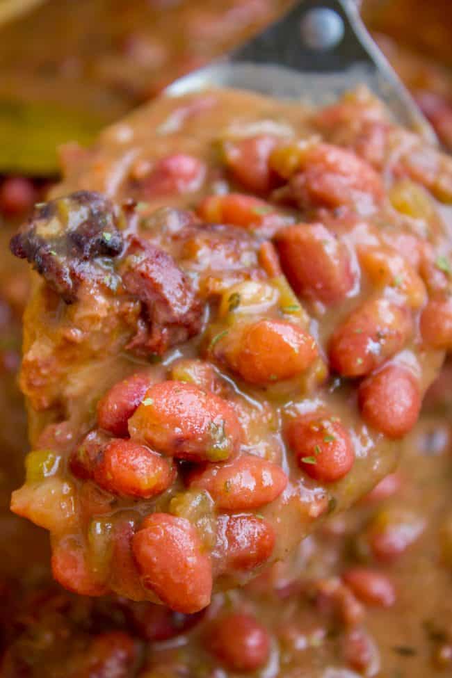 Red Beans and Rice (Better Than Popeye's!) from The Food Charlatan. Have you ever had traditional Red Beans and Rice? It's a southern staple! I tried Popeye's Red Beans and Rice for the first time a while back, but these beans are even better. They are so creamy and flavorful, with the perfect smoky Cajun spice! #redbeansandrice #riceandbeans #beans #rice #ham #hambone #smokey #traditional #southern #cajun #neworleans #popeyes #recipe #easy #stovetop #authentic #withham #Louisiana #best #creamy a big serving spoon of red beans.