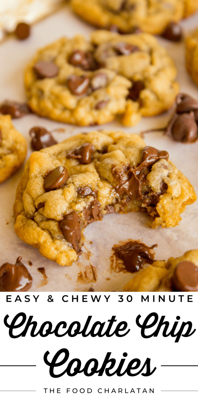 chocolate chip cookies on parchment paper, one with a big bite taken out of it.