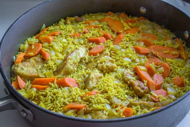 Chicken Biryani (30 Minute Indian Chicken & Rice) from The Food Charlatan. This stove top Chicken Biryani is a delicious 30 minute dinner! You could also call it Indian Chicken and Rice. It's so easy to make and is a healthy weeknight dinner that everyone will love! #chicken #chickendinner #easy #recipe #indian #indianfood #30minutes #dinner #healthy #carrots #onion #cilantro #cashew #stovetop #oneskillet #onepot #rice #basmati #spices #curry #vegetable #skillet chicken biryani cooking in a skillet.
