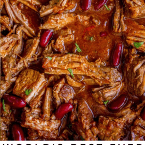Close-up of hearty chili in a slow cooker, featuring shredded beef, kidney beans, and rich red sauce. Garnished with cilantro. Text overlay reads: Worlds Best Ever Slow Cooker Chili - The Food Charlatan. Perfect for a cozy dinner.