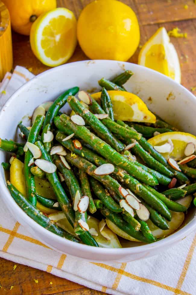 Lemon Dijon Green Beans Almondine from The Food Charlatan. Lemon Dijon Green Beans Almondine is super easy and has tons of flavor! How can you go wrong with butter (and maybe browning it a little?) and lemon and Dijon? You can even make this ahead of time if you plan to serve it for Thanksgiving dinner. #greenbean #almondine #almond #beans #lemon #dijon #mustard #garlic #brownedbutter #butter #sidedish #Thanksgiving #sauteed #fresh #healthy #easy #recipes #withalmonds green beans with lemons and almonds in a pan.