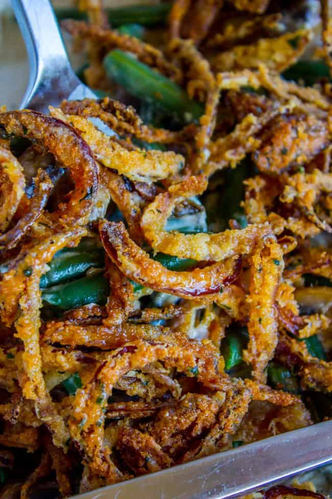 Homemade Green Bean Casserole Recipe from The Food Charlatan. Not your mama's Green Bean Casserole recipe! Let's kick that can of soup out to the curb because the homemade version is LEGIT you guys. Big, bright green beans in a creamy mushroom sauce, topped with crispy fried onions. Thanksgiving doesn't get any better than this! #greenbeans #casserole #frenchs #fromscratch #homemade #thanksgiving #sidedish #easy #fresh #recipe #classic #best #withcheese #foracrowd #makeahead #simple #classic #creamy homemade green bean casserole with crispy fried onions shot up close.