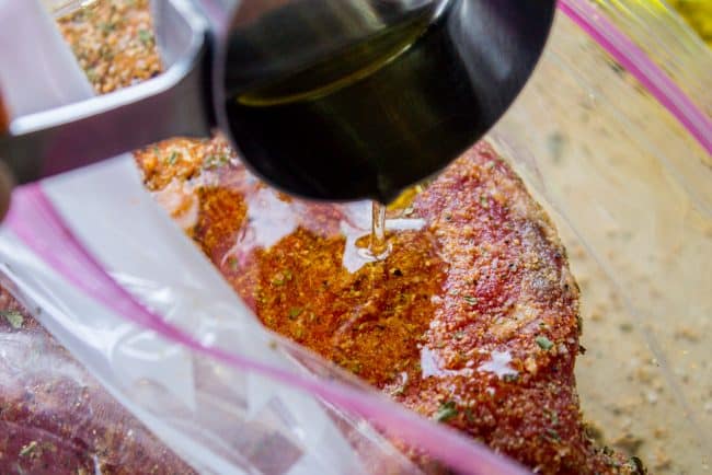 marinade herbs sprinkled over tri tip steak, raw.