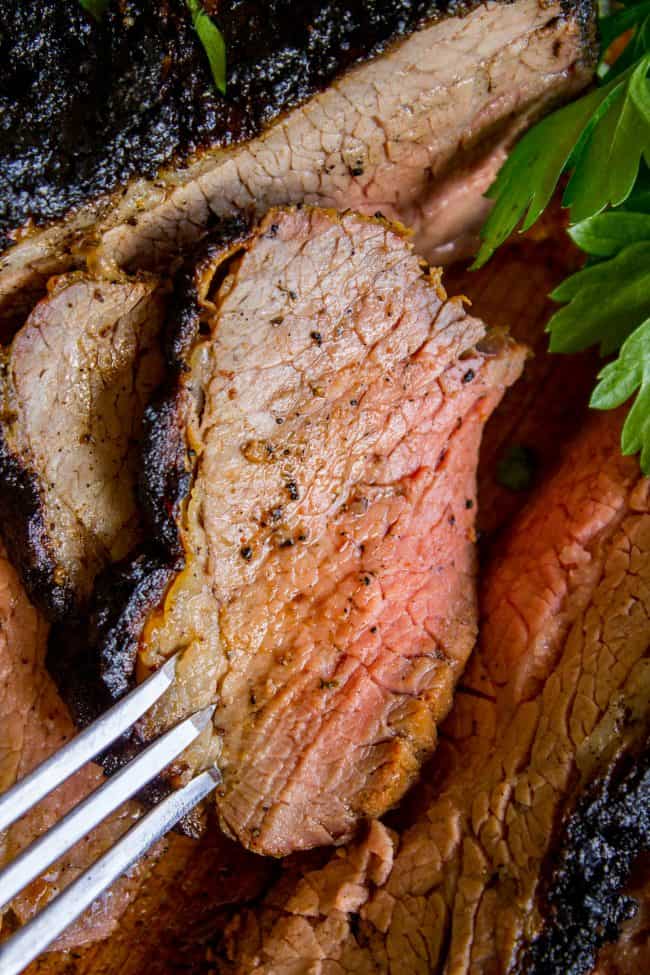 close up of medium rare tri tip with a fork stabbing a slice.