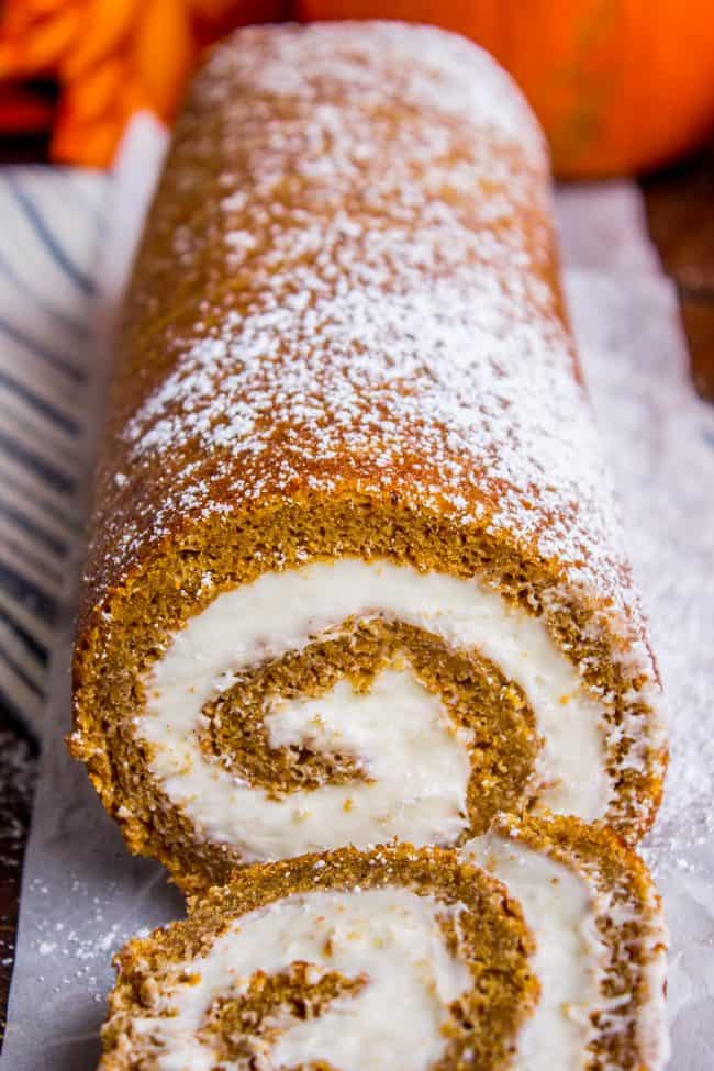 Pumpkin Roll Recipe with Lots of Cream Cheese Frosting from The Food Charlatan. This easy Pumpkin Roll recipe is so impressive and delicious! It's a classic Thanksgiving dessert that you definitely need to make this year. I used LOTS of cream cheese frosting so that it's super moist! #pumpkin #roll #creamcheese #icing #frosting #thanksgiving #christmas #fall #fallbaking #recipe #withcreamcheesefilling #easy #withnutmeg #Libbys #best #homemade #classic #moist #gift #perfect #howtomake #cinnamon pumpkin roll with cream cheese frosting, dusted with powdered sugar.