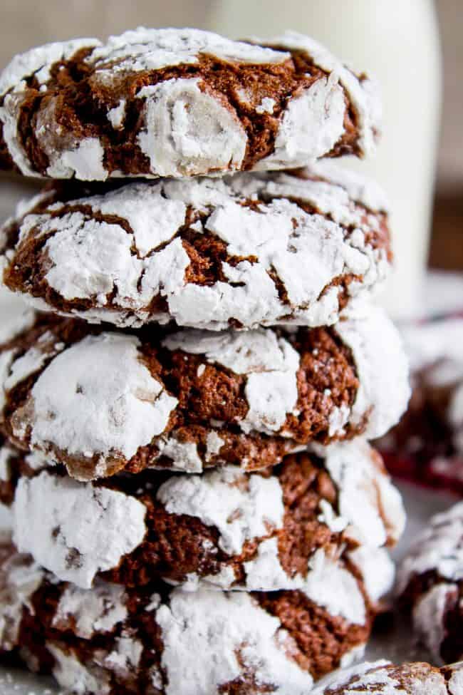 Chocolate Crinkle Cookies (Ultra Fudgy) from The Food Charlatan. It's not even Christmas with Chocolate Crinkle Cookies! They are just a classic. Chocolate Christmas cookies are a must on your cookie plate; they always seem to disappear first. This recipe is ultra fudgy and decadent because we're using cocoa AND baking chocolate! #easy #recipe #classic #chocolate #fudge #fudgy #powderedsugar #crinkle #best #christmas #chewy #brownie #hersheys #withcocoapowder #fromscratch a stack of chocolate crinkle cookies.