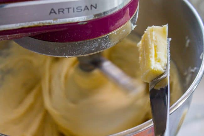 pecan sticky buns recipe showing butter on a knife being dropped into a stand mixer.