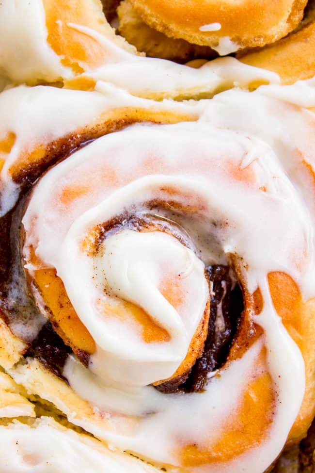 The FLUFFIEST Homemade Cinnamon Rolls of Your Life (Can Make Overnight) from The Food Charlatan. If you haven't made cinnamon rolls with a simple sweet dough (brioche style) instead of regular bread dough, you are totally missing out. These are the FLUFFIEST homemade cinnamon rolls of your life! They are very easy, and you can make them overnight! #cinnamon #cinnamonrolls #creamcheese #frosting #homemade #fluffy #gooey #easy #overnight #cinnabon #recipe #best #fromscratch #icing #makeahead close up of the top of homemade cinnamon rolls.