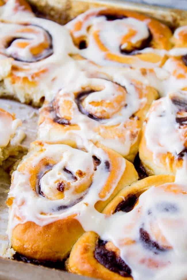 The FLUFFIEST Homemade Cinnamon Rolls of Your Life (Can Make Overnight) from The Food Charlatan. If you haven't made cinnamon rolls with a simple sweet dough (brioche style) instead of regular bread dough, you are totally missing out. These are the FLUFFIEST homemade cinnamon rolls of your life! They are very easy, and you can make them overnight! #cinnamon #cinnamonrolls #creamcheese #frosting #homemade #fluffy #gooey #easy #overnight #cinnabon #recipe #best #fromscratch #icing #makeahead a pan of best cinnamon rolls with icing on top.