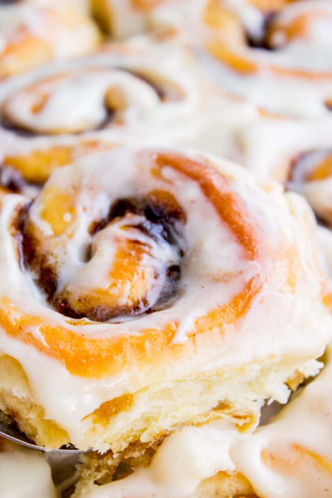 The FLUFFIEST Homemade Cinnamon Rolls of Your Life (Can Make Overnight) from The Food Charlatan. If you haven't made cinnamon rolls with a simple sweet dough (brioche style) instead of regular bread dough, you are totally missing out. These are the FLUFFIEST homemade cinnamon rolls of your life! They are very easy, and you can make them overnight! #cinnamon #cinnamonrolls #creamcheese #frosting #homemade #fluffy #gooey #easy #overnight #cinnabon #recipe #best #fromscratch #icing #makeahead cinnamon rolls with icing shot from close up.