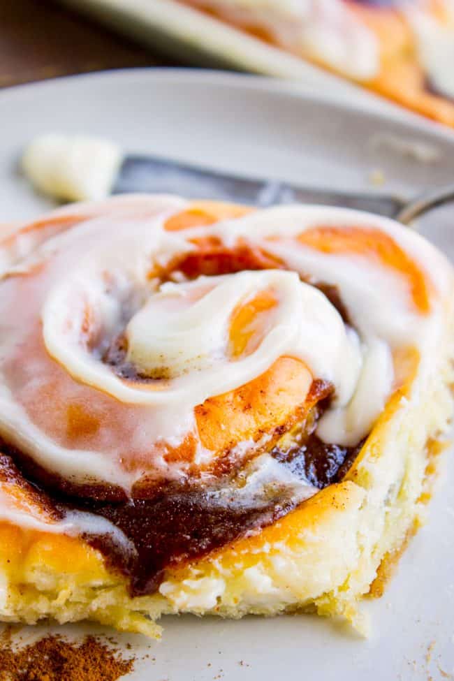 The FLUFFIEST Homemade Cinnamon Rolls of Your Life (Can Make Overnight) from The Food Charlatan. If you haven't made cinnamon rolls with a simple sweet dough (brioche style) instead of regular bread dough, you are totally missing out. These are the FLUFFIEST homemade cinnamon rolls of your life! They are very easy, and you can make them overnight! #cinnamon #cinnamonrolls #creamcheese #frosting #homemade #fluffy #gooey #easy #overnight #cinnabon #recipe #best #fromscratch #icing #makeahead cinnamon roll showing swirl of frosting on top.