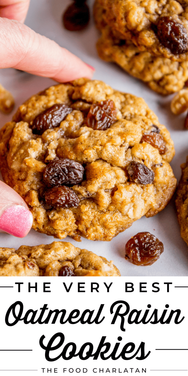 hand lifting an oatmeal raisin cookie from a cookie sheet.